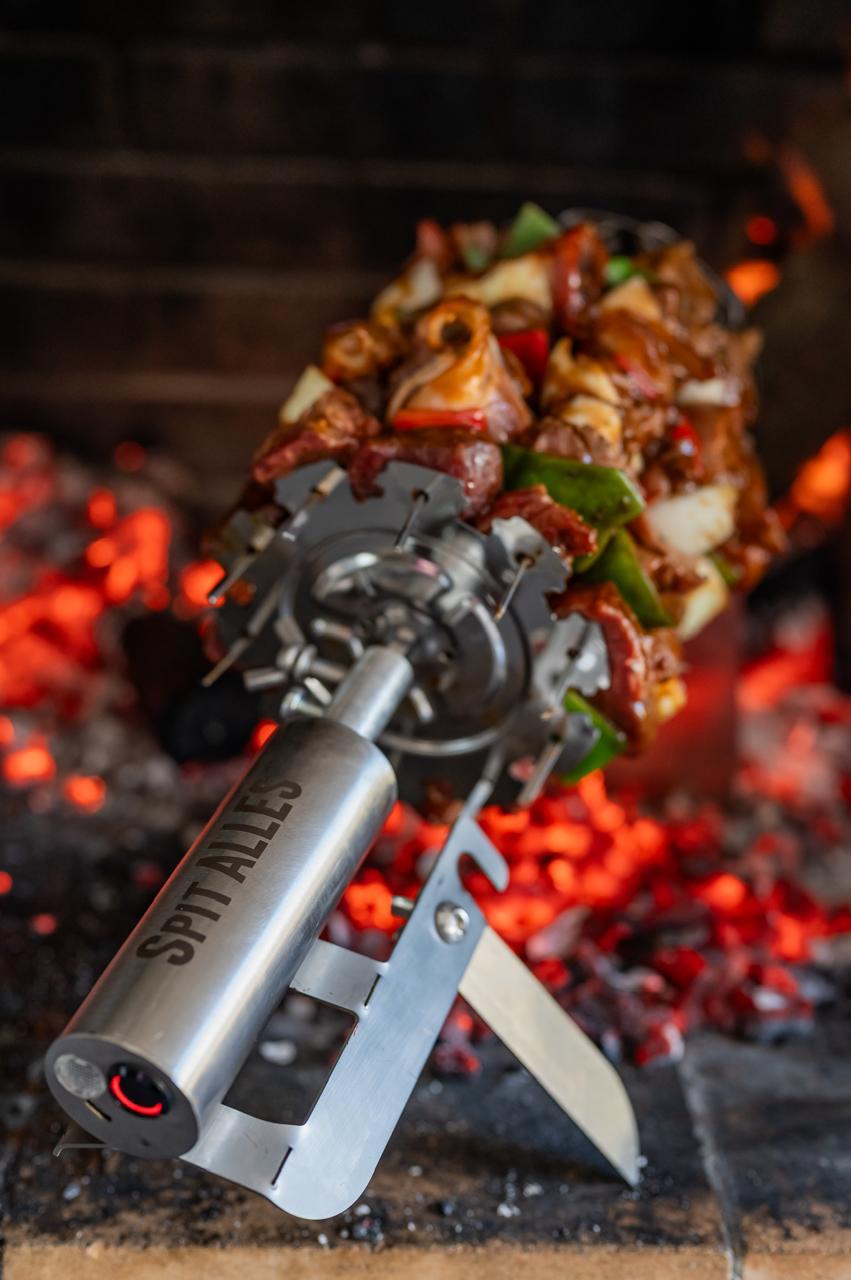 A loaded kebab skewer of meat and peppers on the SpitAlles carousel head over glowing coals