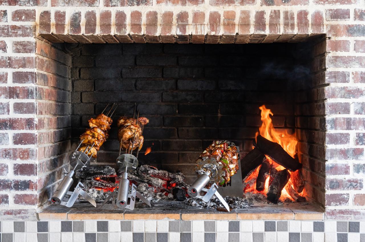A SpitAlles rotisserie turning over a brick fireplace